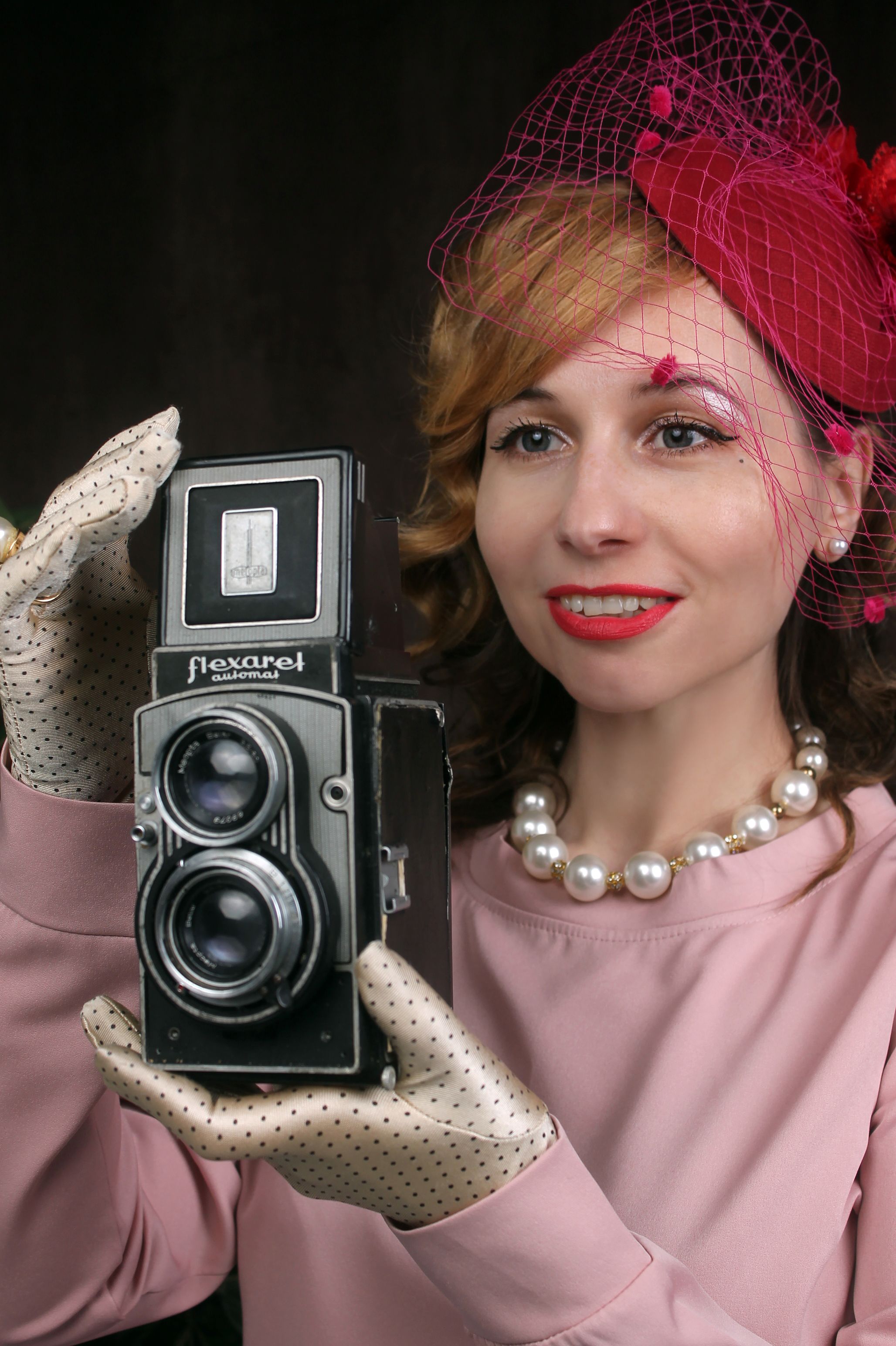 Woman in vintage attire holding a retro camera with elegant accessories.