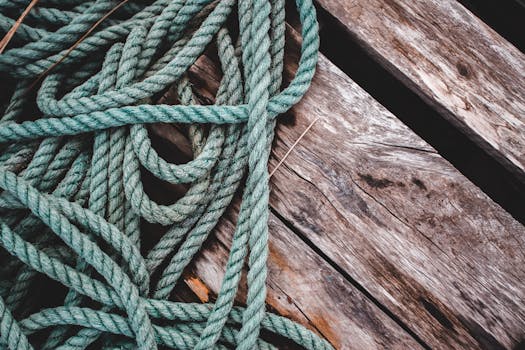 Detailed close-up of green rope on a weathered wooden surface, showcasing texture and color contrast.