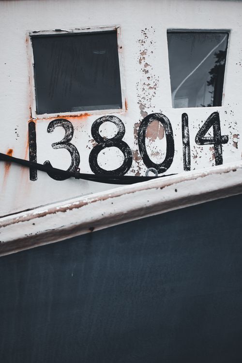 Free Detailed view of weathered numbers on an old fishing boat hull, showing rust and decay. Stock Photo