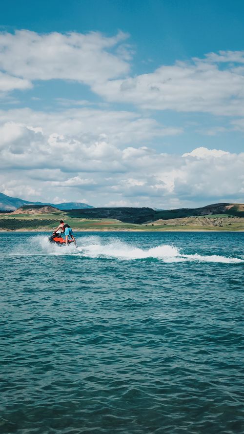 Free A thrilling ride on a jetski across a tranquil lake under a clear blue sky. Stock Photo