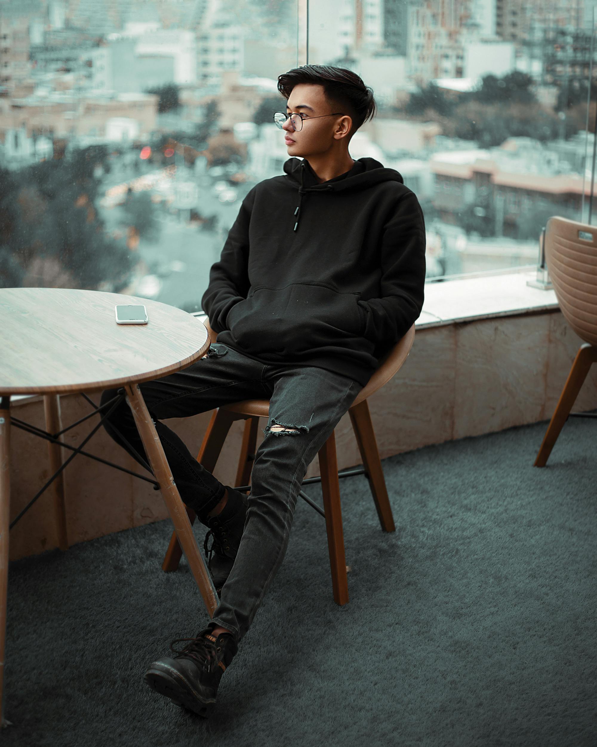 a man in black jacket sitting on brown wooden chair