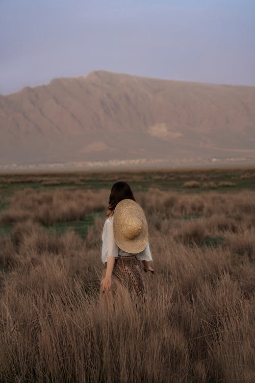 A Woman Standing on Brown Field