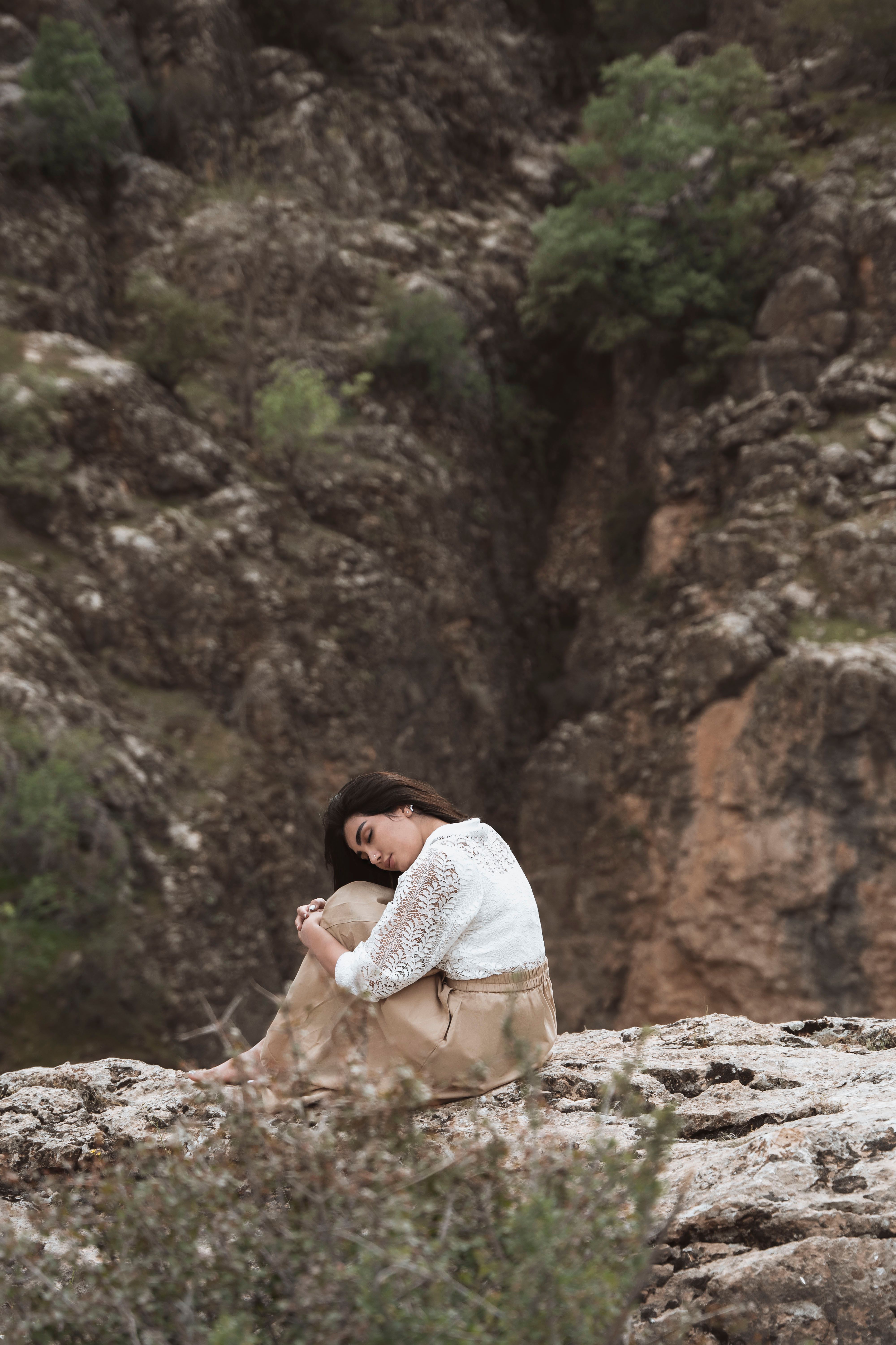 A Woman in White and Brown Dress Sitting on the Rock Formation · Free ...