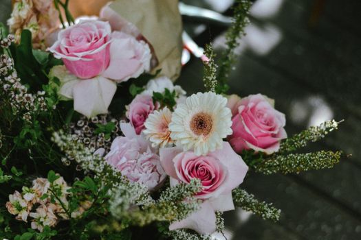 A close-up of assorted pink roses and white daisies in a beautiful floral arrangement.