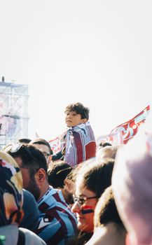 A vibrant outdoor gathering featuring a diverse crowd waving colorful flags.