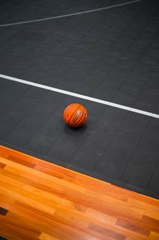 A single basketball on an indoor court, emphasizing the sport's dynamic energy and focus.