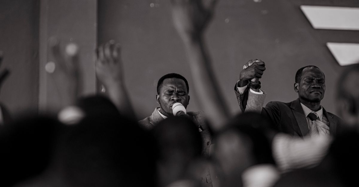 pastor preaching passionately on a stage with congregation raising hands