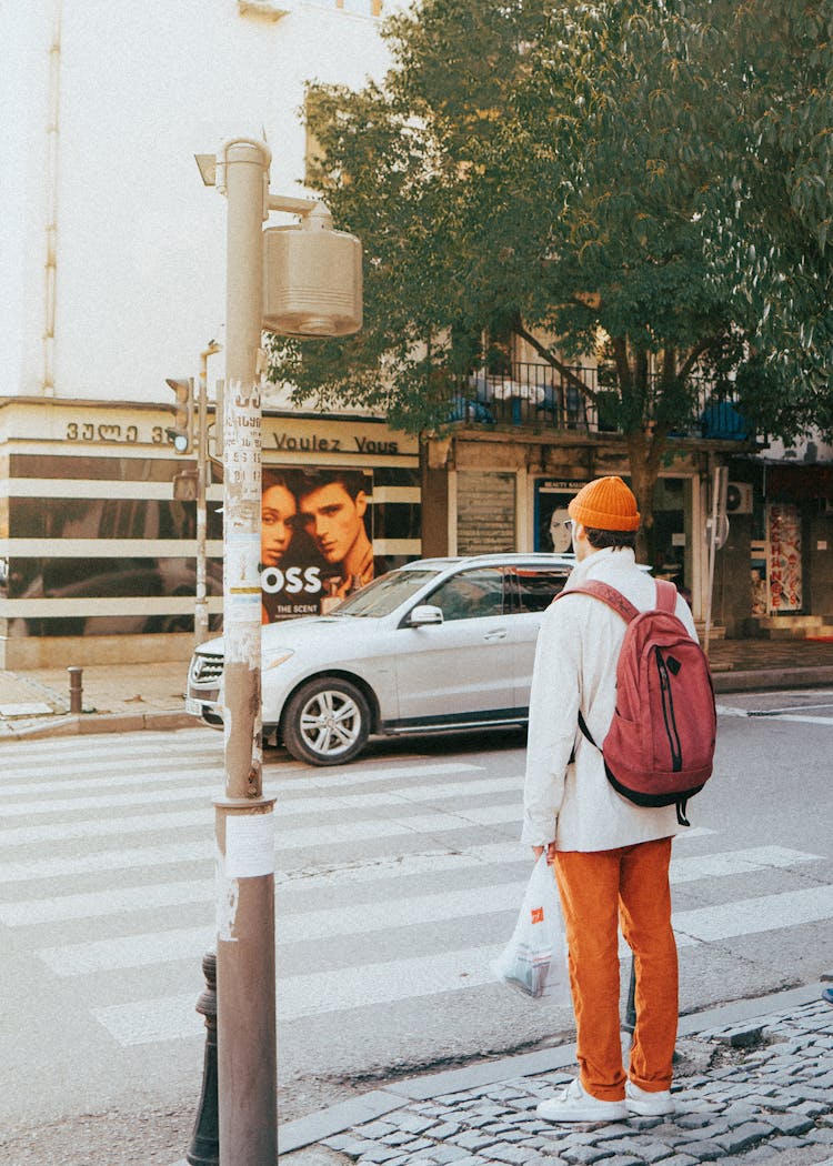 A Man Carrying Red Backpack Standing On The Roadside 