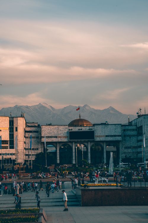 Free A bustling urban plaza with people and a mountainous backdrop during the day. Stock Photo