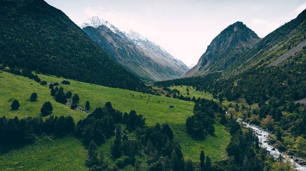 A stunning aerial view of green valleys and towering mountains in Chunkurchak, Kyrgyzstan.