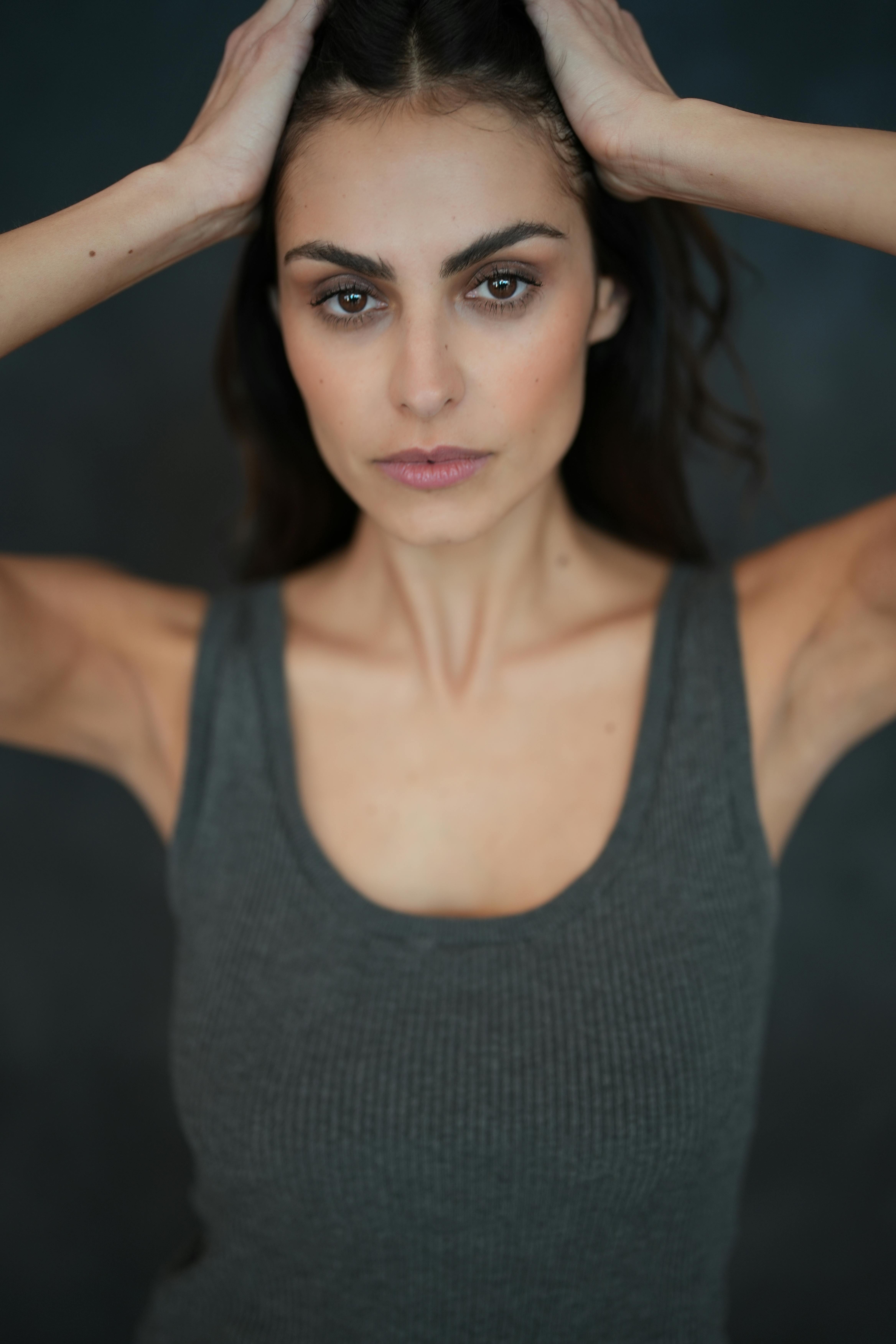 A striking portrait of a woman in a gray tank top with a focused expression, highlighting natural beauty and confidence.