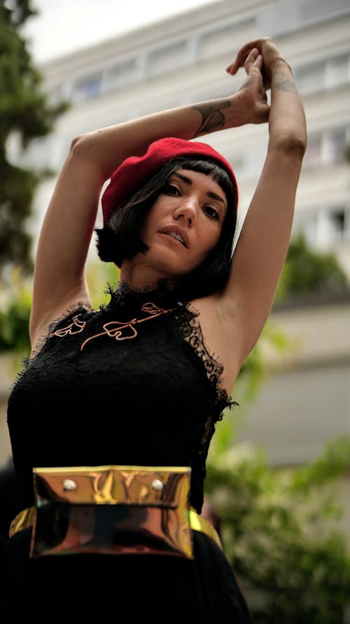 Woman in a Black Dress and Red Beret Posing with Arms Raised