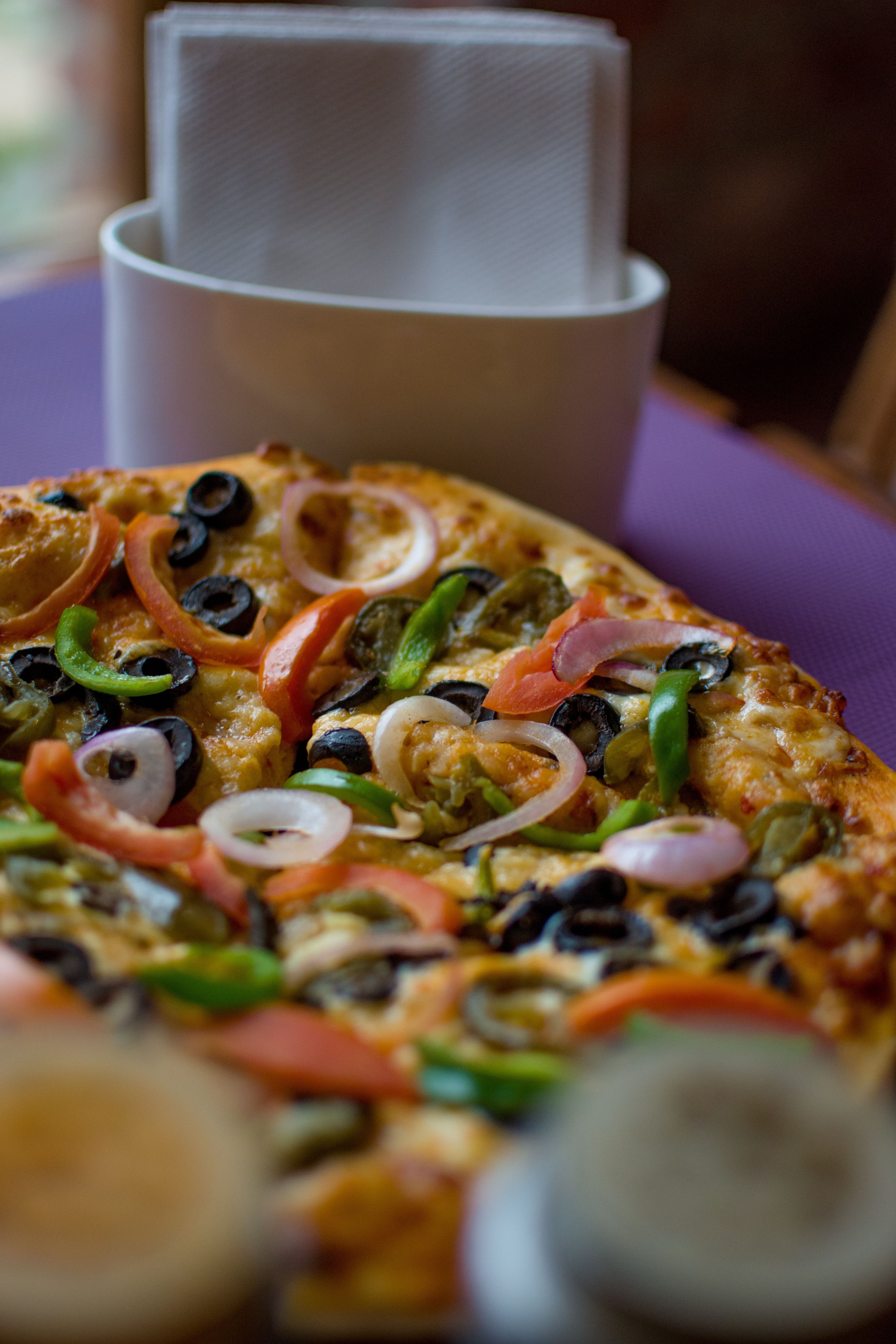 Close-up of a vibrant vegetable pizza topped with olives, onions, and peppers.