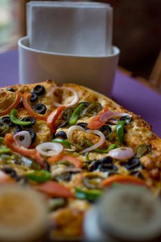 Close-up of a vibrant vegetable pizza topped with olives, onions, and peppers.