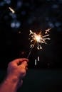Selective Focus Photography Person Holding Lighted Sparkler at Nighttime