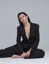Barefoot Brunette Woman in Black Suit Sitting on Floor