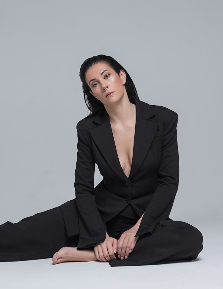 Barefoot Brunette Woman In Black Suit Sitting On Floor