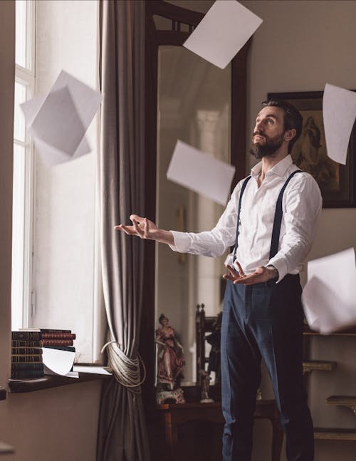 Man in White Long Sleeves and Black Pants Throwing Papers 