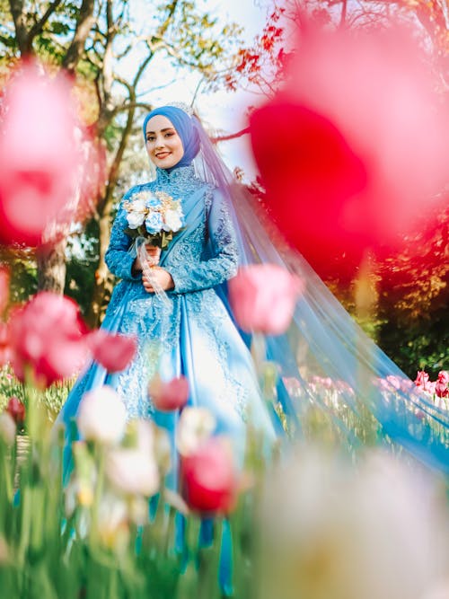 A Woman in Blue Wedding Gown Holding a Bouquet of Flowers