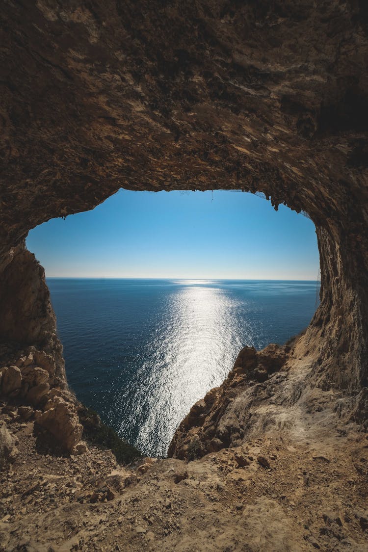 Reflection Of Sunlight On The Sea Viewed Through A Hole In A Rock Formation