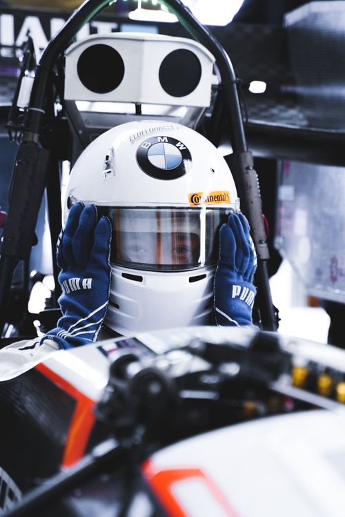 Free Race car driver putting on helmet in vehicle, ready for competition. Stock Photo
