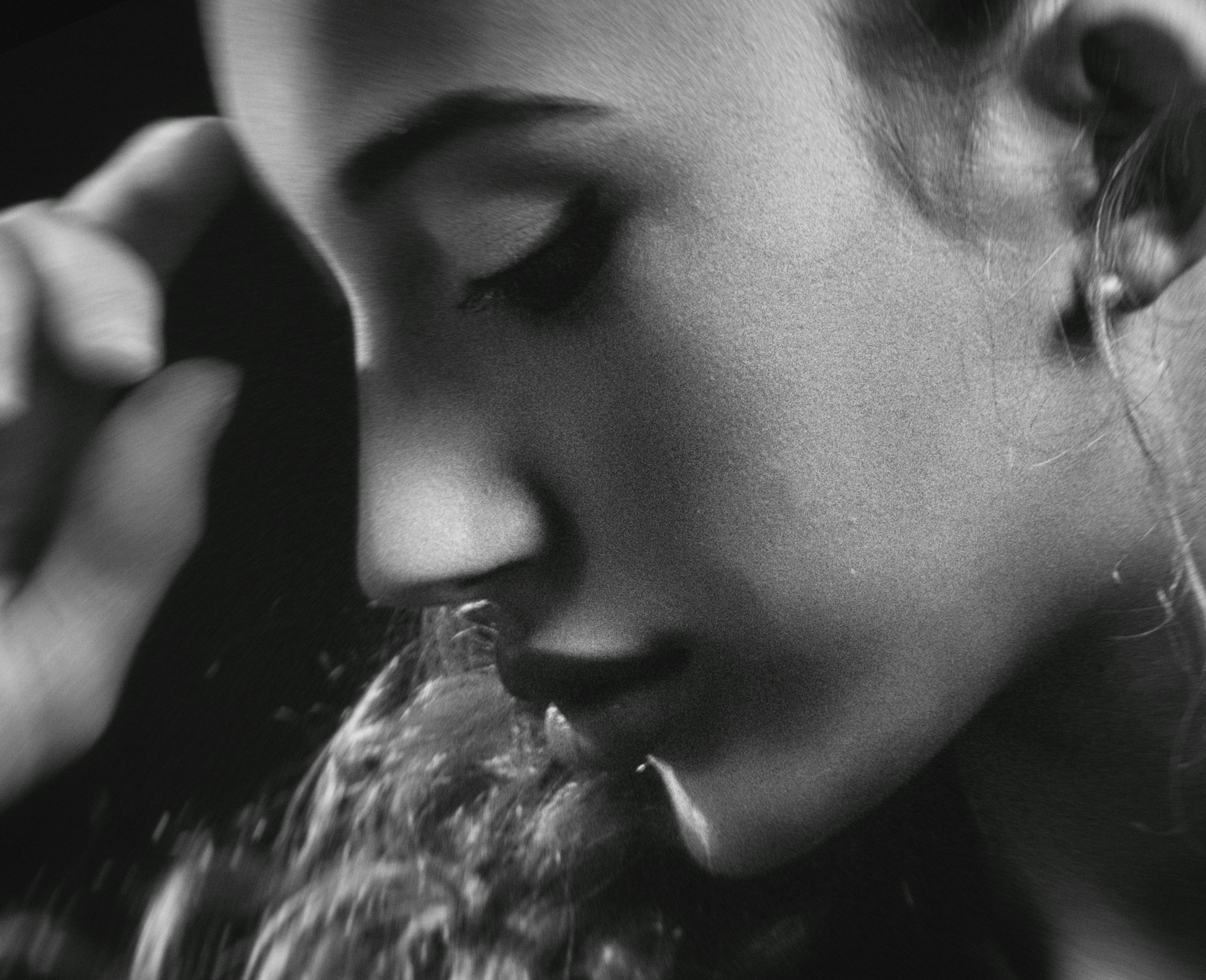 Close-up black and white artistic portrait of a young woman with closed eyes.