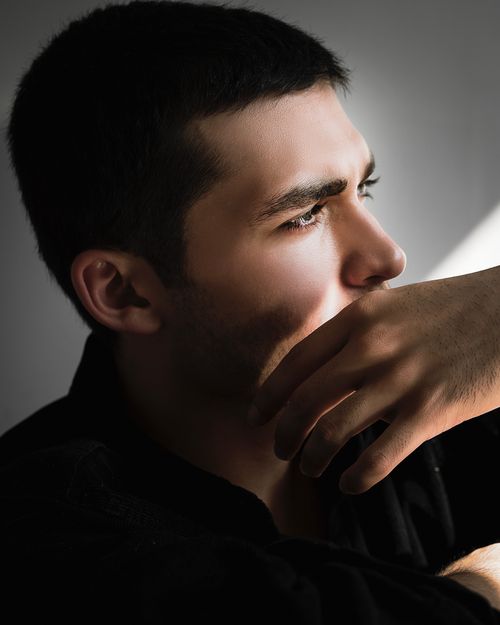 Free Profile portrait of a young man in sunlight, expressing contemplation. Stock Photo