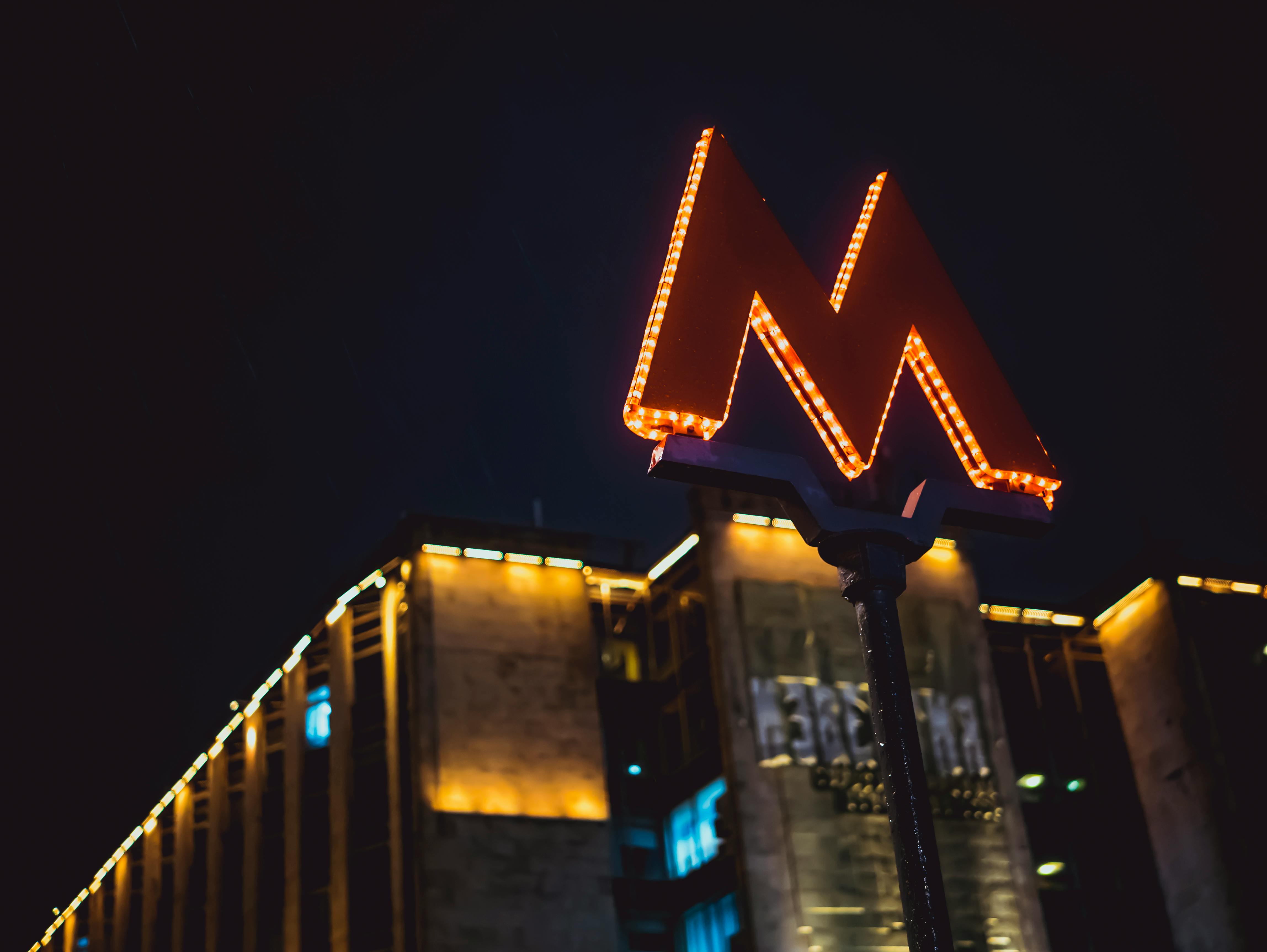 Low Angle Photography of Lighted M Road Sign during Nighttime