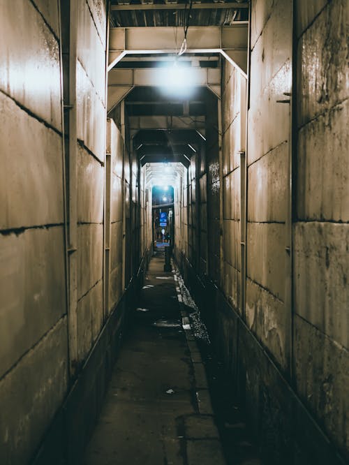 Narrow Corridor With White Light Bulb on Top