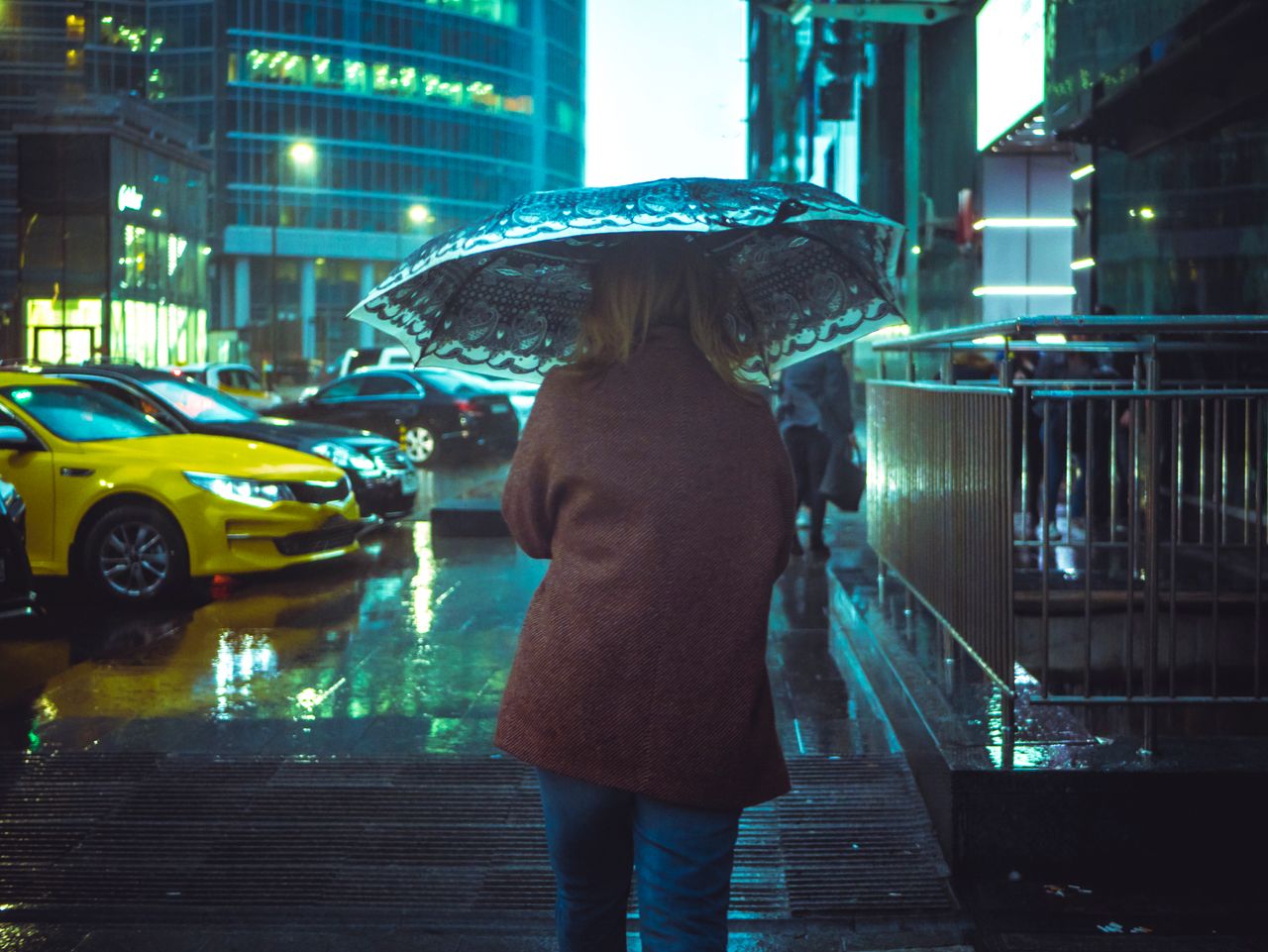Woman with an umbrella walking on a rainy city street at night