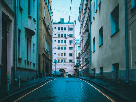 Street view of narrow urban alley surrounded by ancient architectural buildings and a parked car.