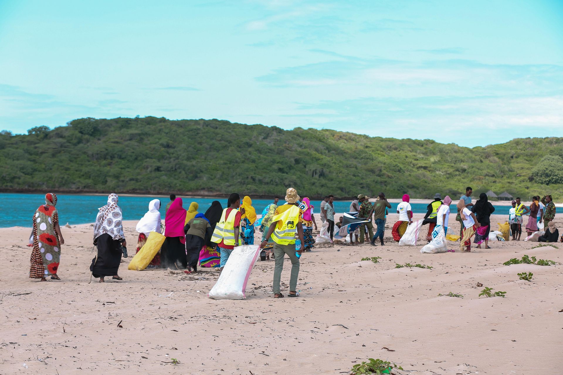 A diverse group participates in a community beach cleanup in Lamu, Kenya.