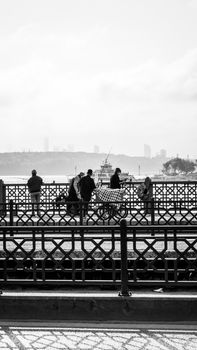 Monochrome cityscape capturing people by the waterfront with a view of Istanbul's skyline.