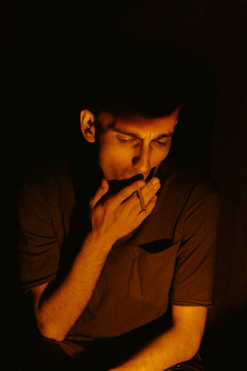 Free Low light portrait of a man smoking, creating a dramatic and moody atmosphere. Stock Photo