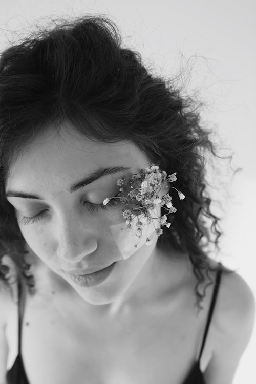 Free Girl with Dark Curly Hair with Tiny Flowers Attached to Cheek Stock Photo