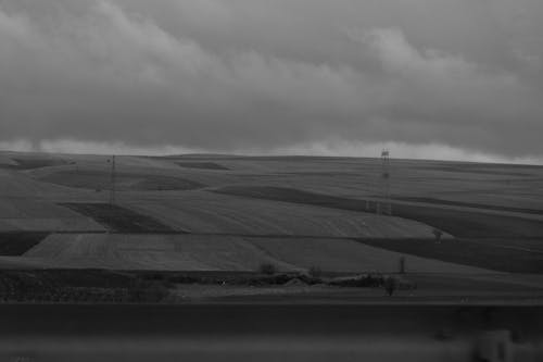 Grayscale Photo of Agricultural Lands Under Cloudy Sky