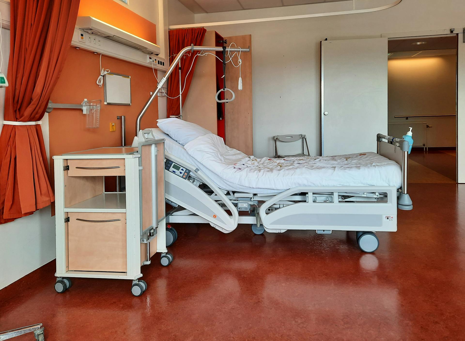 A clean and modern hospital room equipped with an adjustable bed and medical equipment.