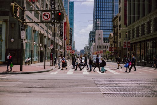 People crossing a busy street in downtown San Francisco on a sunny day.