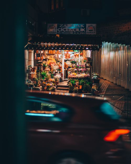 Free A cozy flower shop illuminated at night on an urban street, creating a warm and inviting atmosphere. Stock Photo