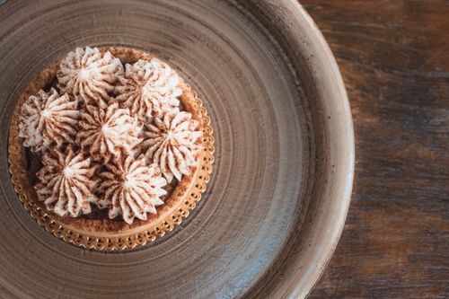 Free A close-up shot of a beautifully decorated cream tart pastry on a wooden plate, perfect for food photography. Stock Photo