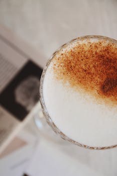 Close-up image of a cappuccino with a cinnamon topping served in a glass.