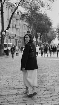 A woman in a city street captured in black and white, looking back as she walks.