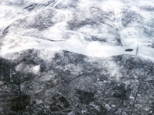 Free Stunning aerial view of Vladivostok covered in snow, featuring clouds and ice-covered landscape. Stock Photo