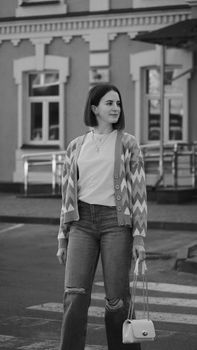 Stylish woman in casual wear standing confidently on a city street crosswalk.