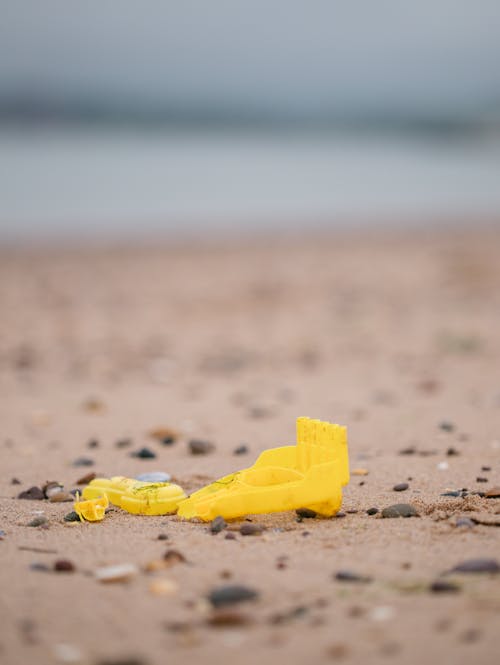 Free Yellow Plastic Toy on Brown Sand Stock Photo