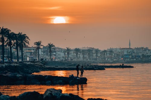 Foto profissional grátis de beira-mar, céu alaranjado, cidade