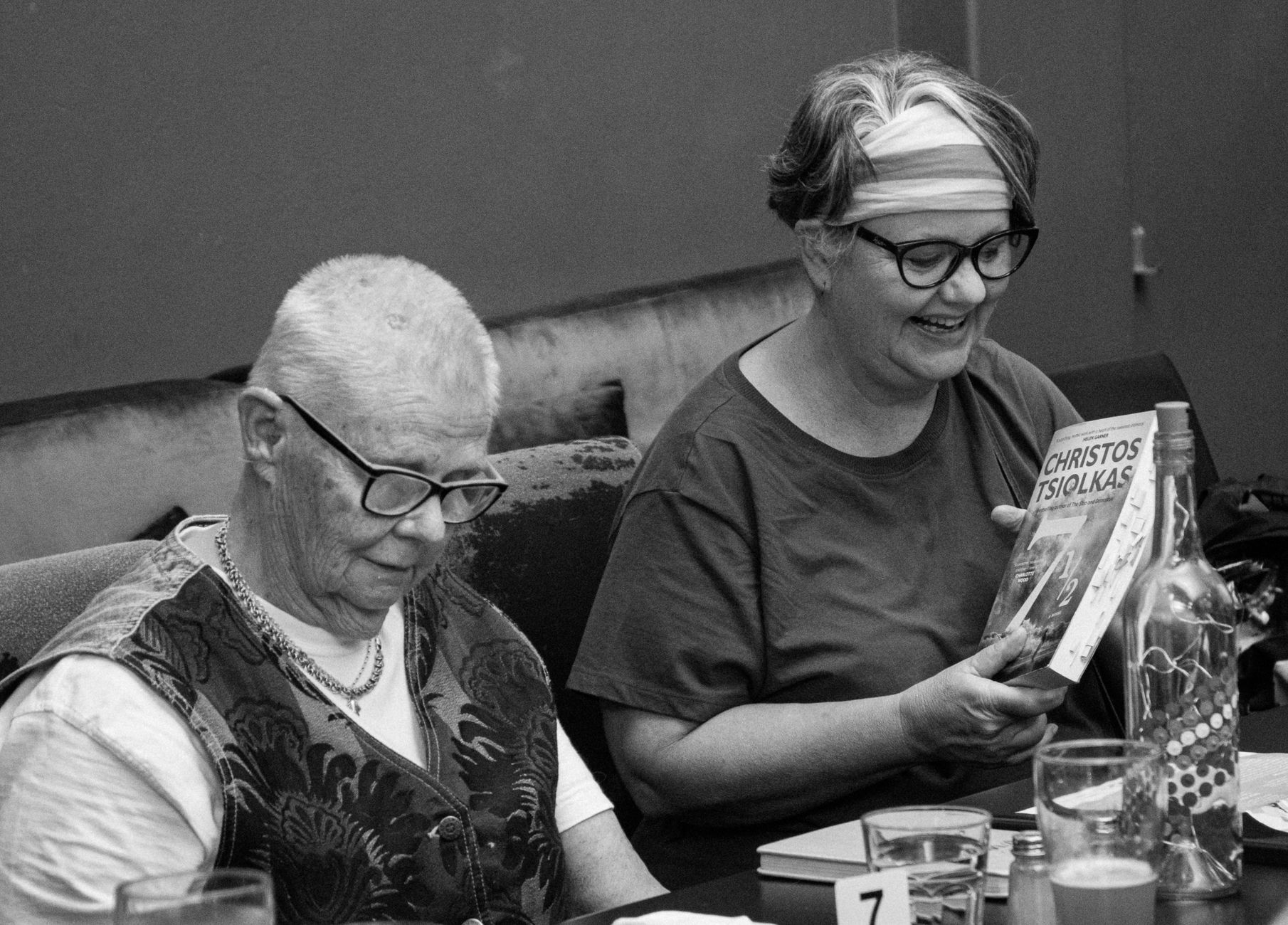 Two senior women reading and enjoying books together in a cozy indoor setting.