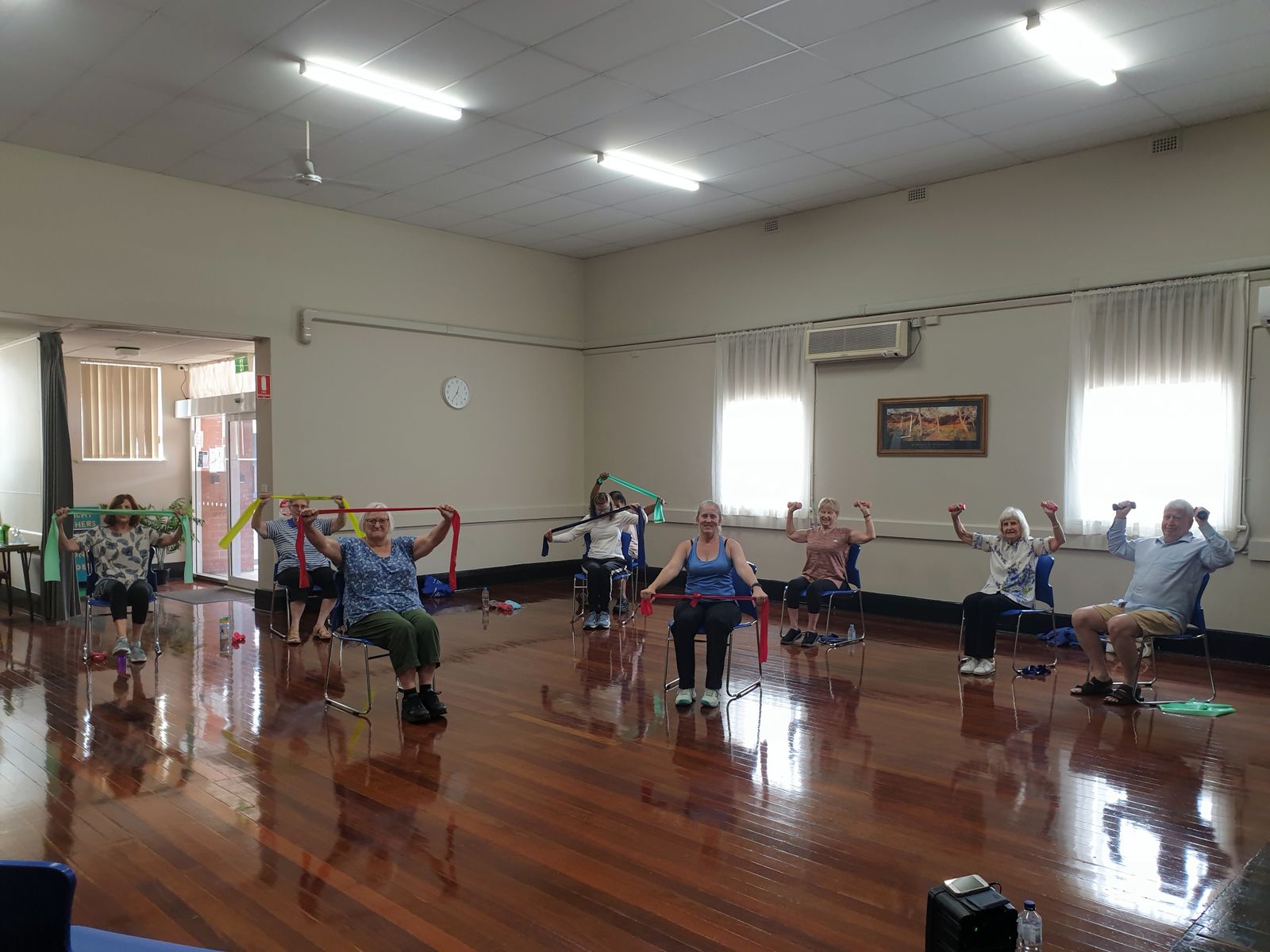 Group of active seniors practicing chair yoga and seated exercises together in a community class