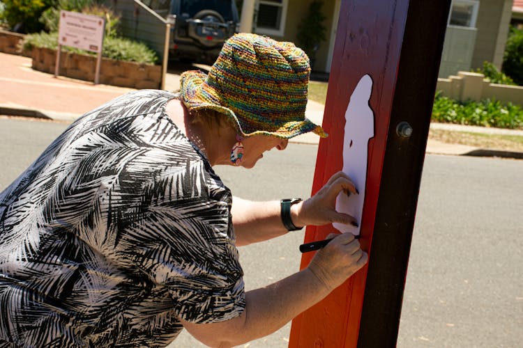 Elderly Woman Tracing A Cutout On A Wood Plank