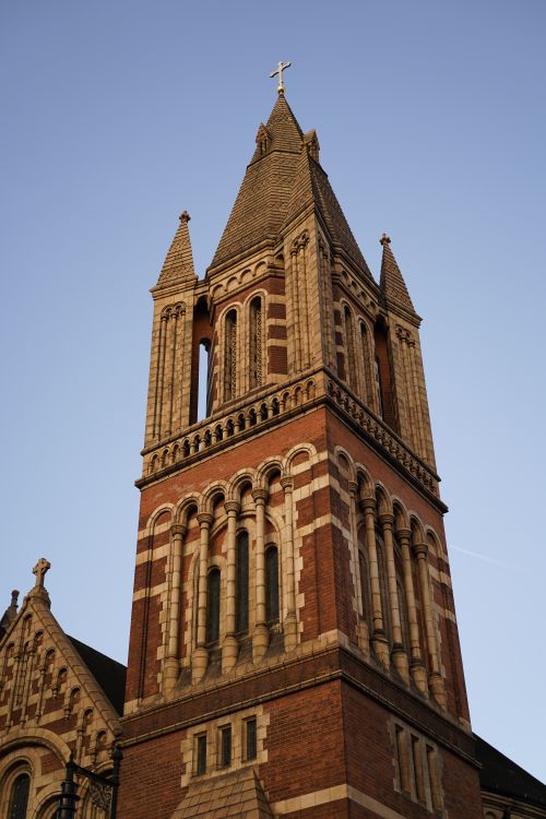 Free Low angle view of a Gothic church tower with intricate details against a clear evening sky. Stock Photo
